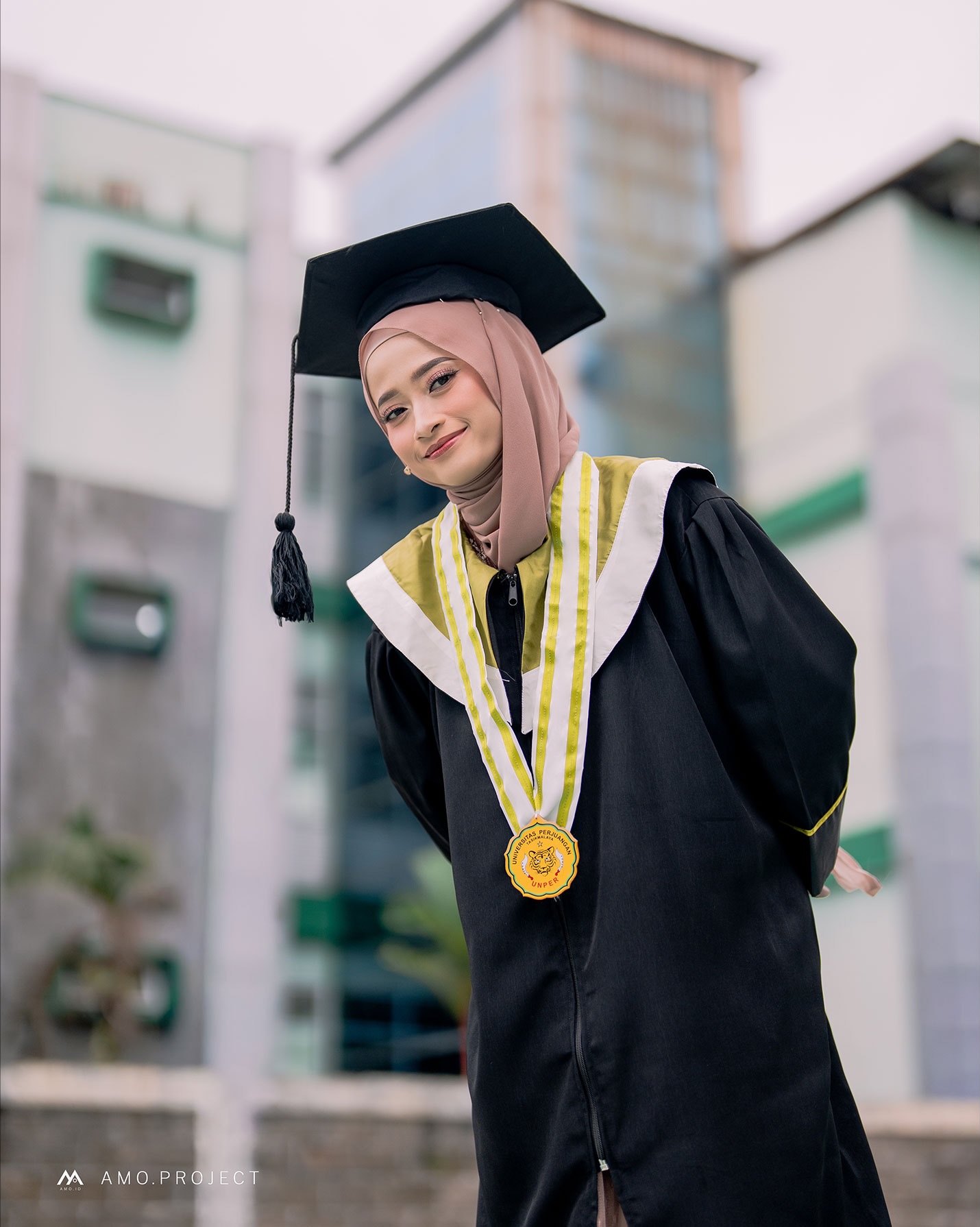 Wisudawati berpose mengenakan toga dan medali